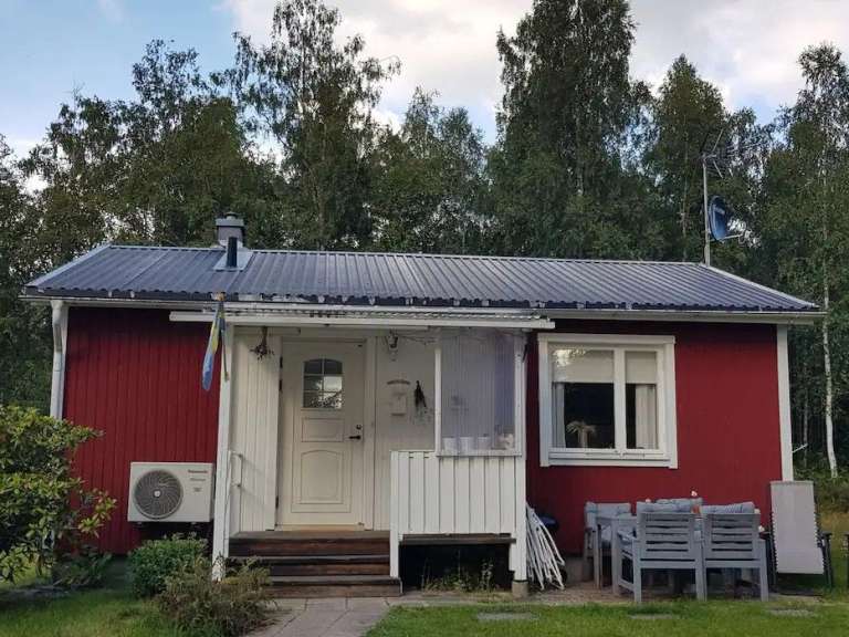 Ein rotes Haus mit einer weißen Tür und einem schwarzen Dach