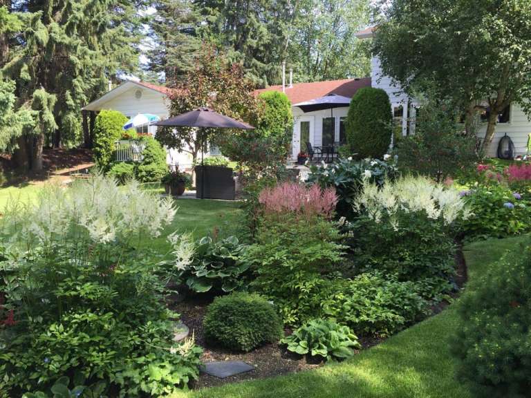 Ein Garten mit vielen Blumen und einem Haus im Hintergrund