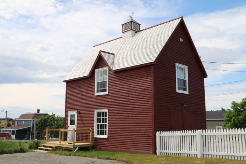 Ein rotes Haus mit weißem Dach und einem weißen Zaun