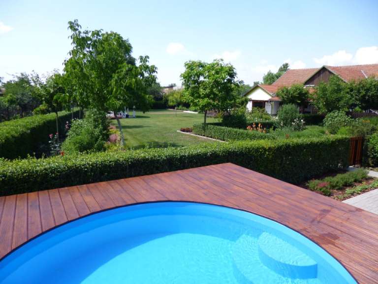 Ein blauer Pool auf einem Holzdeck in einem Garten
