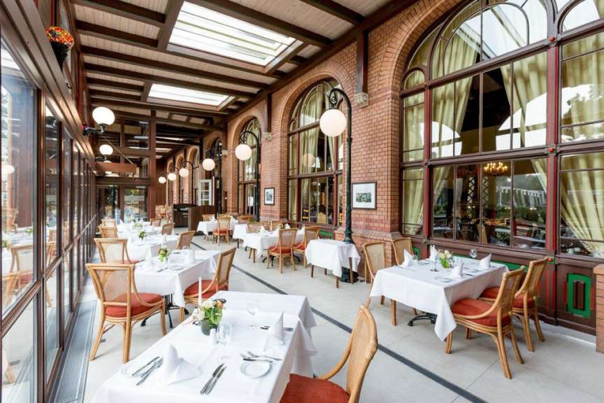 Ein eleganter Speisesaal mit vielen Fenstern und Ziegelwänden, gedeckten Tischen und vielen Stühlen.