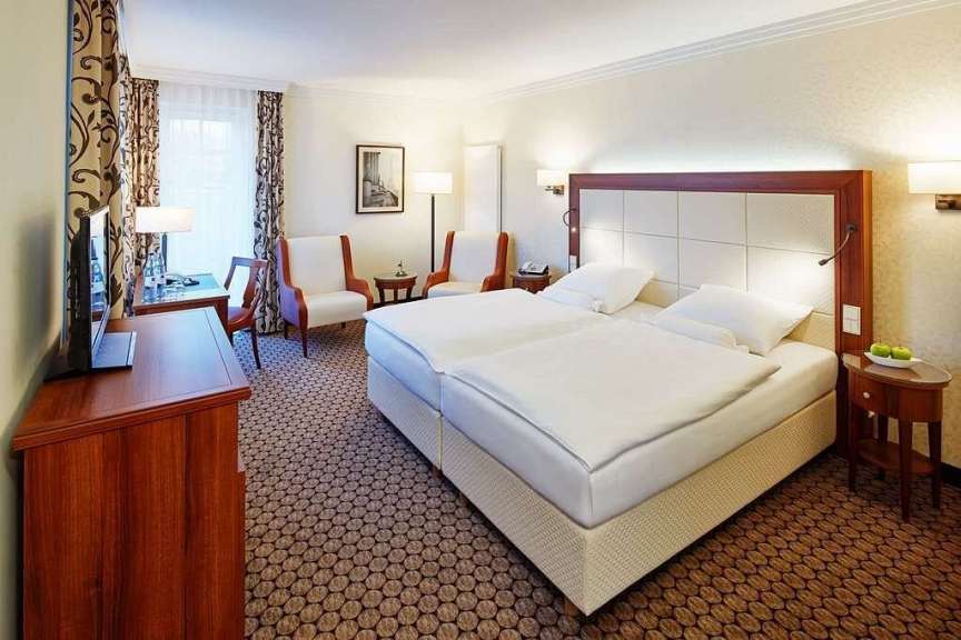 Ein Hotelzimmer mit zwei Betten, einem Schreibtisch und zwei Sesseln.