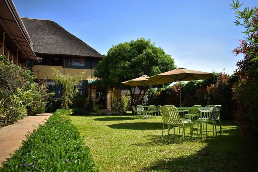 Ein Garten mit Tisch und Stühlen und Regenschirmen vor einem Haus
