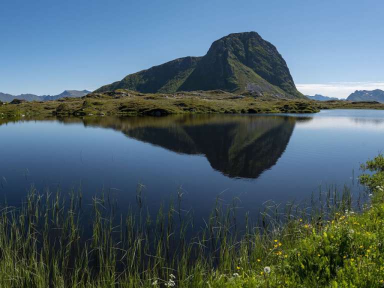 Ein Berg spiegelt sich im Wasser eines Sees