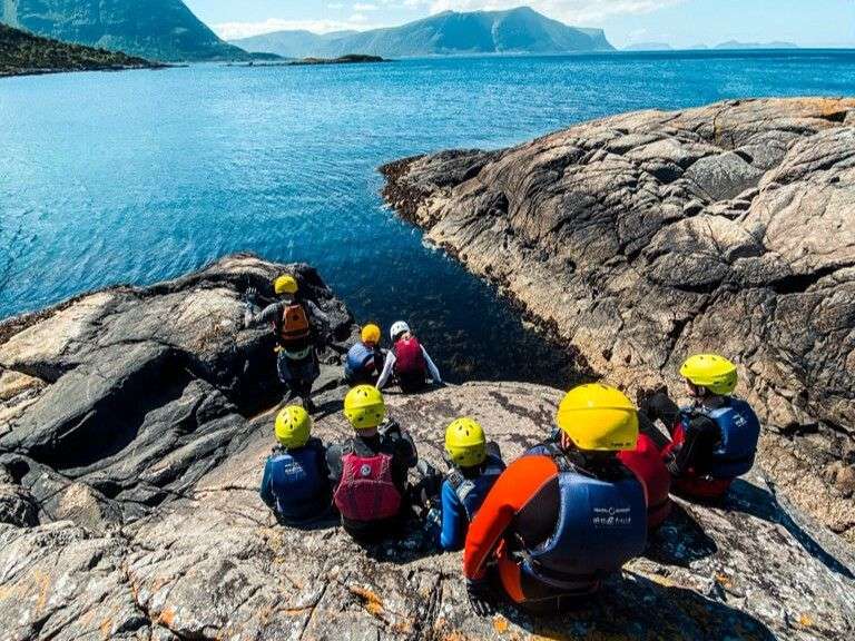 Eine Gruppe von Menschen sitzt auf einem Felsen in der Nähe des Ozeans