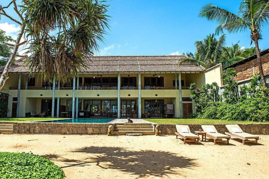Ein großes Haus mit einem Pool und Liegestühlen im Vordergrund