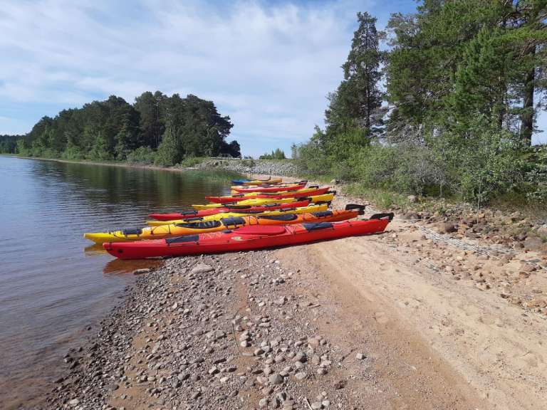 Eine Reihe roter und gelber Kajaks am Ufer eines Sees