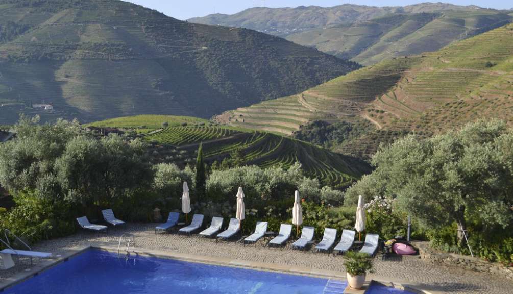 Ein Pool mit Stühlen und Sonnenschirmen umgeben von Bergen