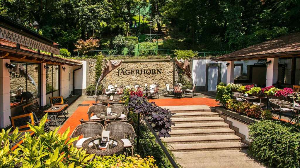 Eine Terrasse mit Tischen und Stühlen vor einem Gebäude mit der Aufschrift jagerhorn