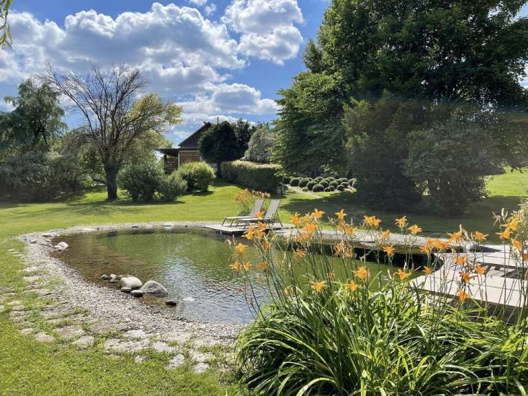 Ein Garten mit einem Teich und Liegestühlen