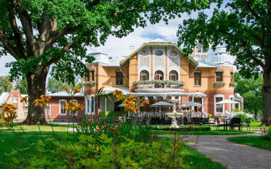 Ein großes Gebäude mit vielen Bäumen und Stühlen davor