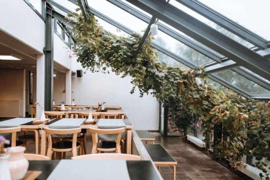 Tische und Stühle in einem Restaurant mit Blättern an der Decke