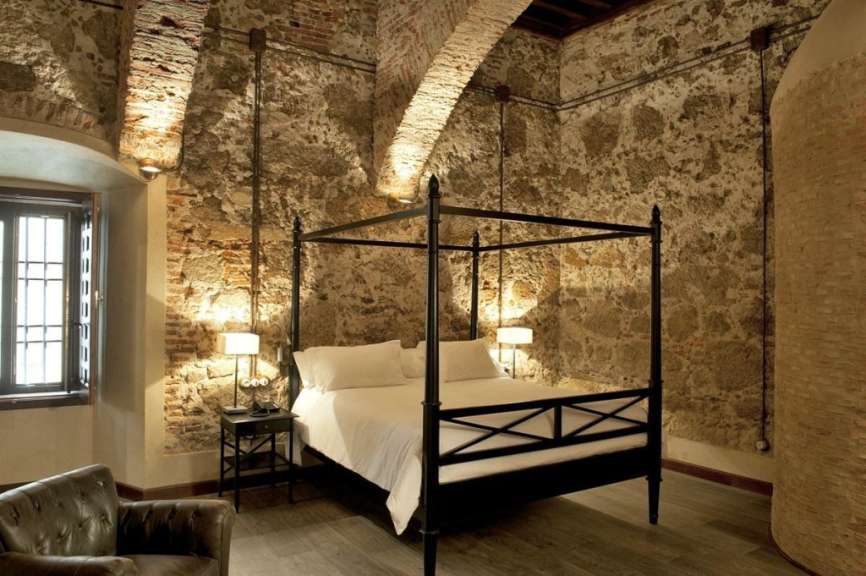 Ein Schlafzimmer mit einem Himmelbett und einer Backsteinmauer