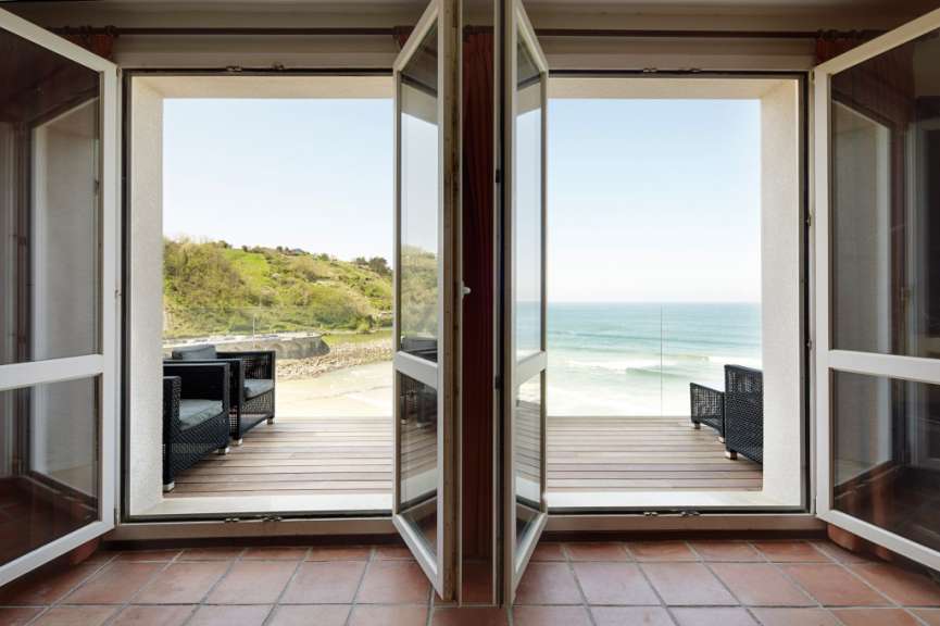 Ein Wohnzimmer mit offenen Fenstern mit Blick auf den Ozean