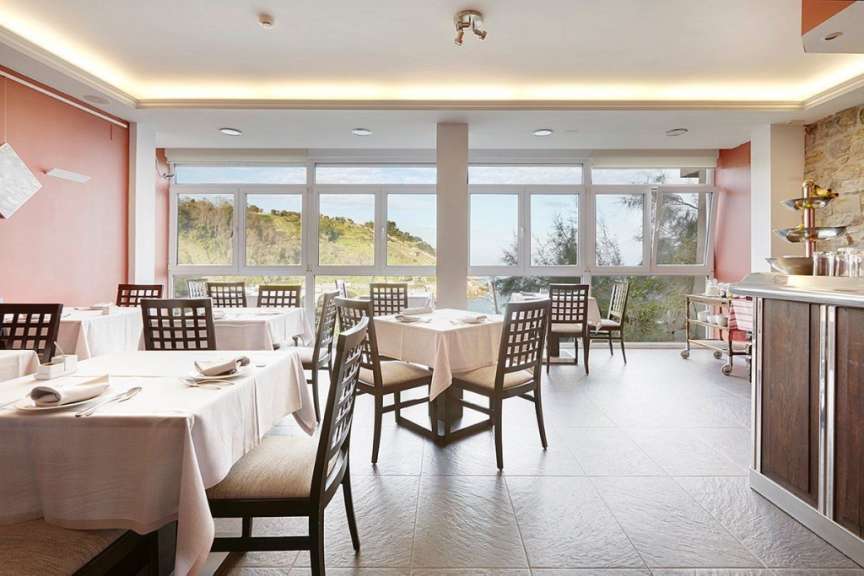 Tische und Stühle in einem Restaurant mit vielen Fenstern