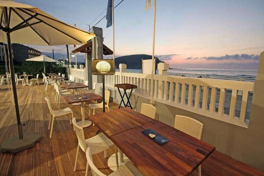 Eine Terrasse mit Holztischen und Stühlen und einem Sonnenuntergang im Hintergrund