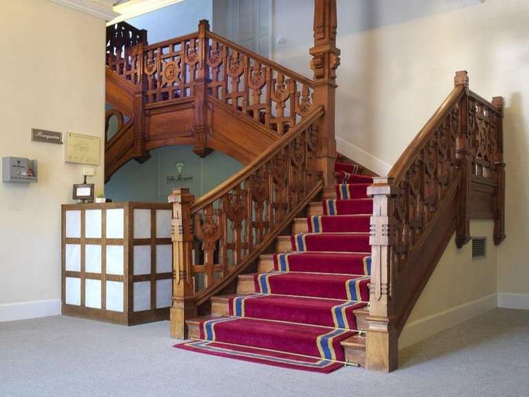 Eine hölzerne Treppe mit einem roten Teppich in einem Gebäude