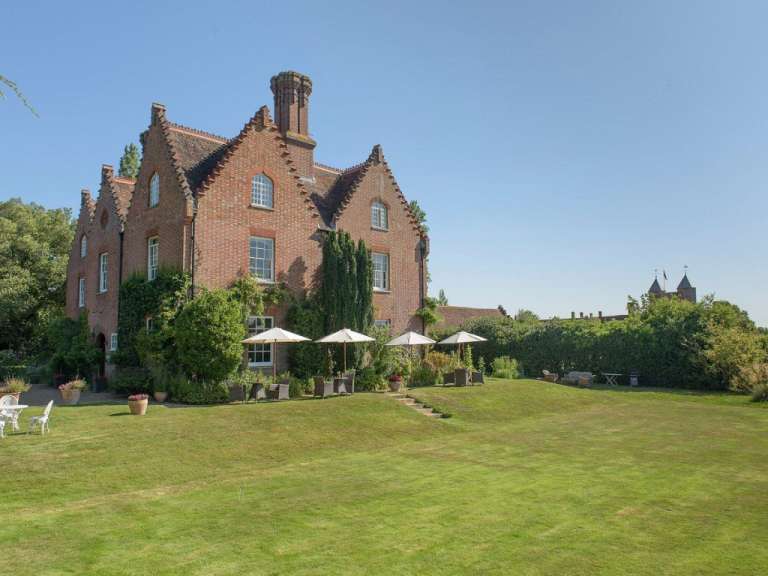 Ein großes Backsteingebäude mit vielen Sonnenschirmen und Stühlen