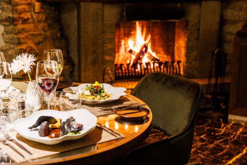 Ein Tisch mit Essen und Gläsern vor einem Kamin