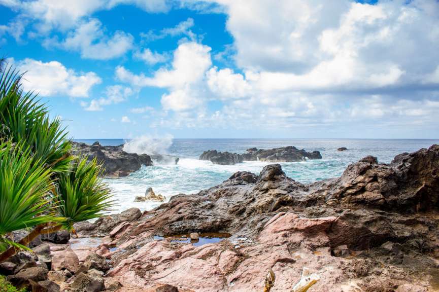Eine felsige Küste mit einem blauen Himmel und weißen Wolken im Hintergrund