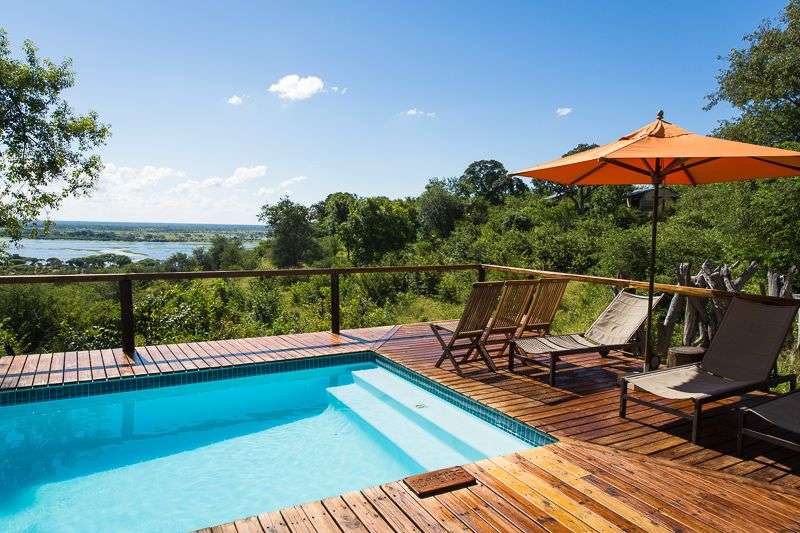 Ein Swimmingpool auf einem Holzdeck mit Blick auf einen Fluss