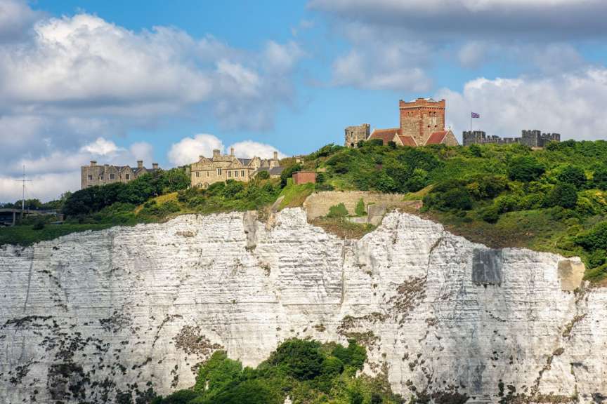 Ein großes Schloss sitzt auf einem Hügel über einem weißen Felsen