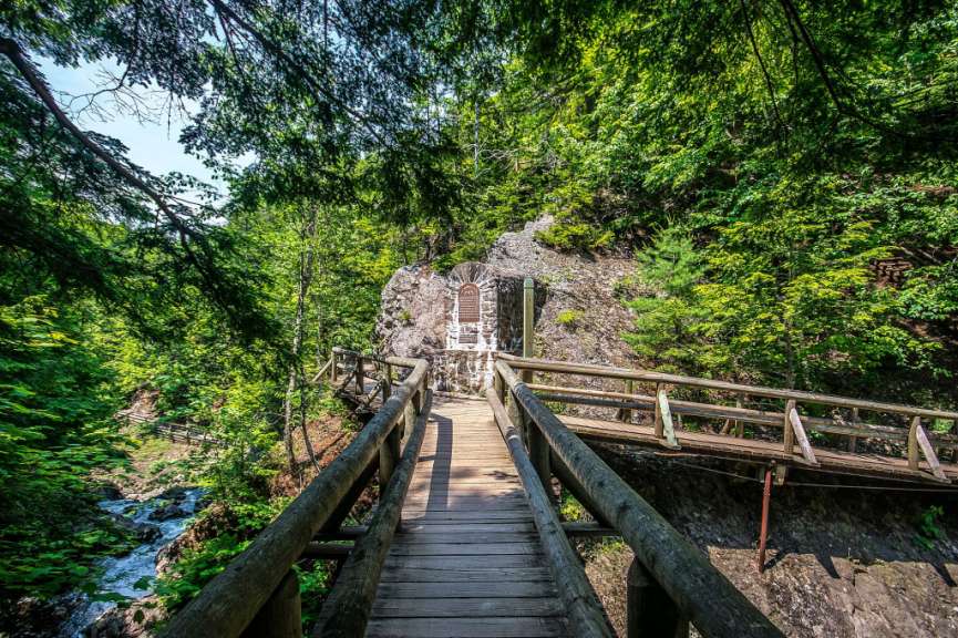 Eine Holzbrücke führt zu einem Wasserfall im Wald