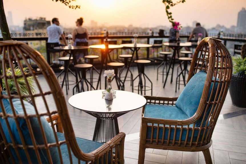 Tische und Stühle auf einer Terrasse mit Blick auf die Stadt bei Sonnenuntergang