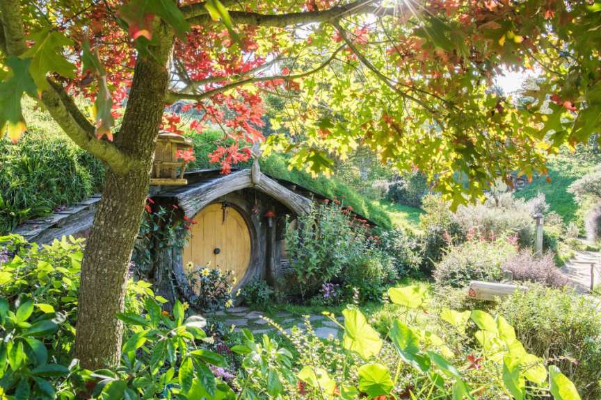 Ein kleines Haus mit einer runden Tür in einem Garten