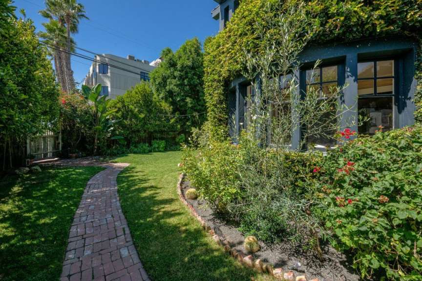 Ein Backsteinweg führt durch einen Garten in der Nähe eines Hauses