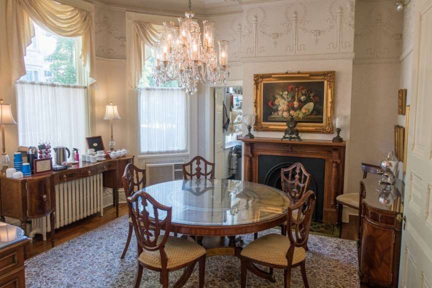 Ein Esszimmer mit einem Tisch und Stühlen und einem Gemälde an der Wand