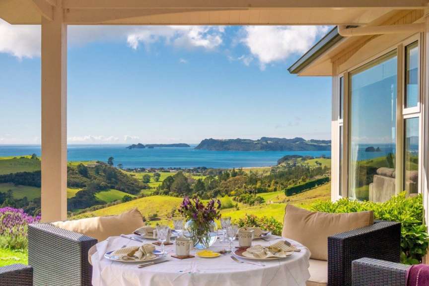 Ein Tisch mit Tellern und Gläsern auf einer Veranda mit Blick auf das Meer