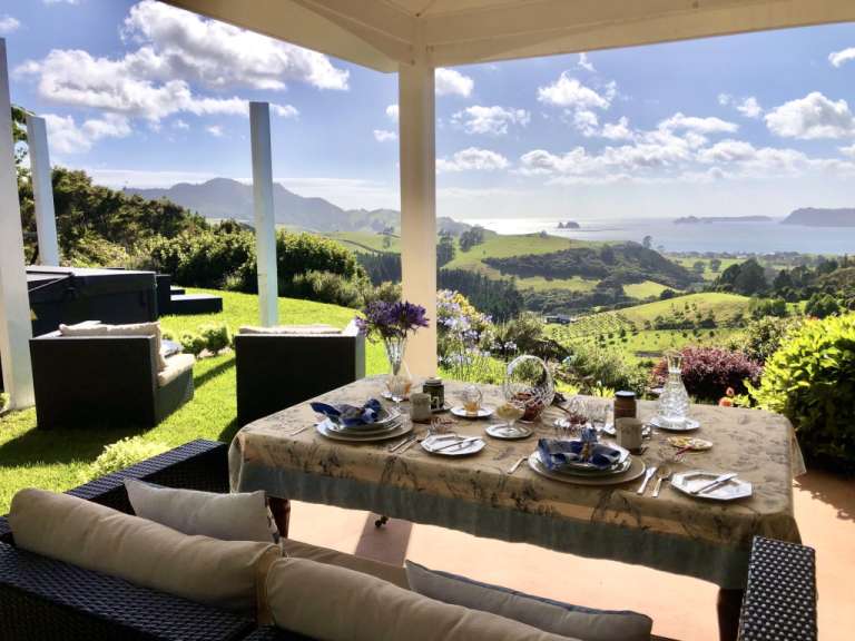 Ein Tisch mit Tellern und Gläsern auf einer Veranda mit Blick auf den Ozean