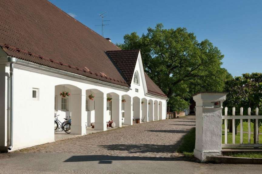 Ein weißes Gebäude mit einem braunen Dach und einem weißen Zaun