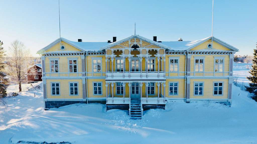 Ein großes gelbes Haus mit vielen Fenstern im Schnee