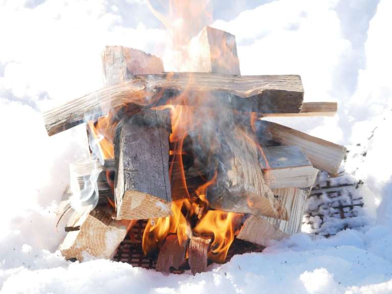 Ein Haufen Holz brennt im Schnee