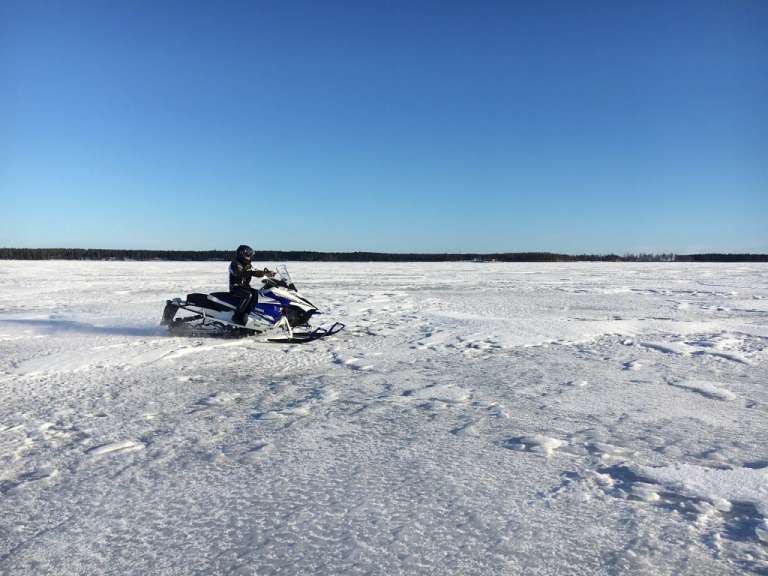 Ein Mann fährt mit einem Schneemobil auf einem schneebedeckten Feld