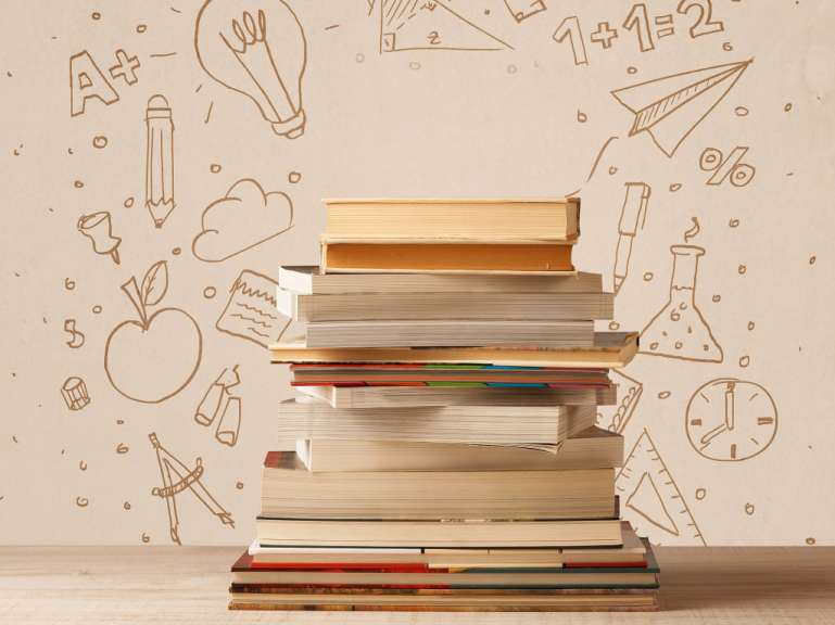 Ein Stapel Bücher steht vor einer Wand mit Handgezeichneten Symbolen