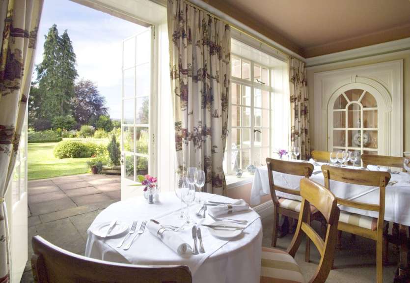 Ein Tisch und Stühle in einem Restaurant mit Blick auf einen Garten