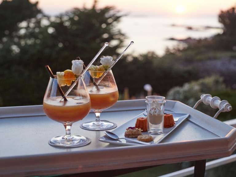Ein Tablett mit zwei Cocktails und Desserts darauf