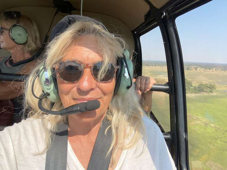 Eine Frau mit Kopfhörern und Sonnenbrille sitzt in einem Hubschrauber