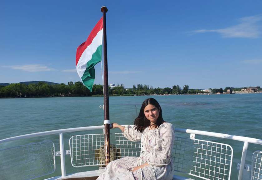 Carolin Alberti in Ungarn Eine Frau sitzt auf einem Boot mit einer ungarischen Flagge im Hintergrund