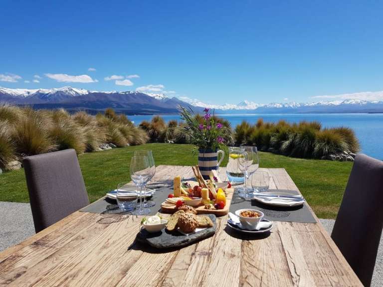 Ein Holztisch mit einem Tablett mit Essen und Weingläsern darauf