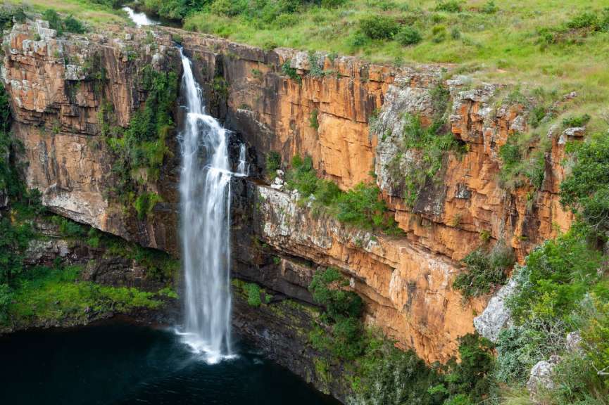 Ein Wasserfall stürzt von einer Klippe in einen Teich
