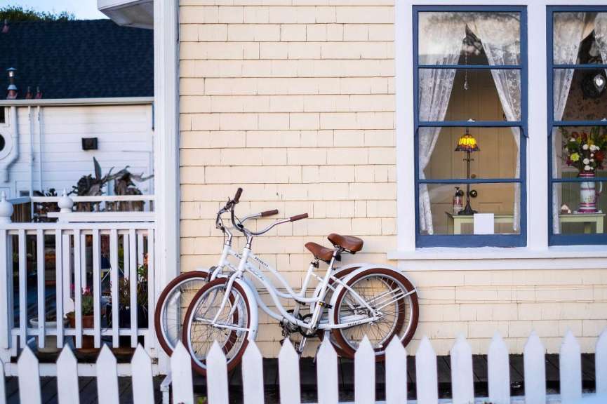 Ein weißes Fahrrad steht vor einem gelben Haus