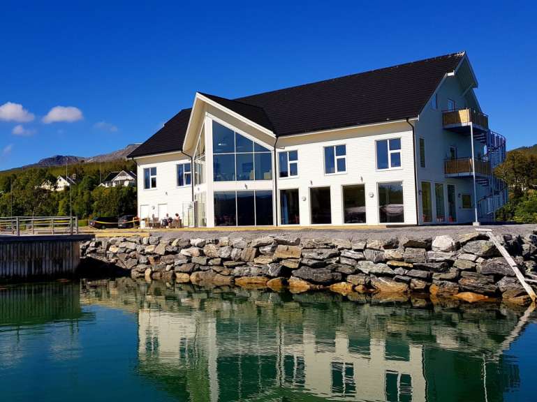 Ein großes weißes Haus mit vielen Fenstern steht neben einem See