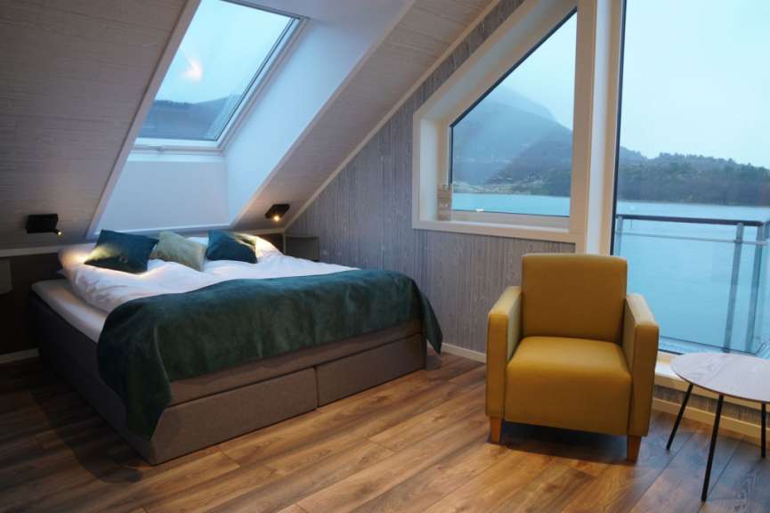 Ein Schlafzimmer mit einem Bett und einem Stuhl mit Blick auf einen See