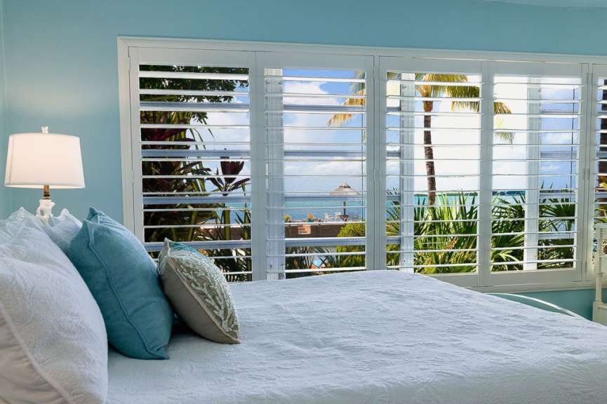 Ein Schlafzimmer mit Fensterläden und einem Bett mit blauen Kissen