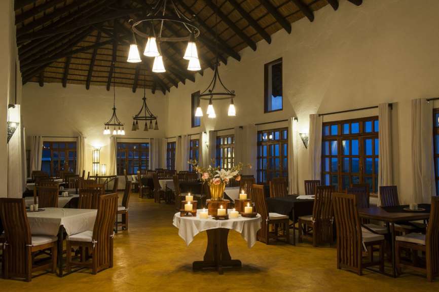 Ein Esszimmer mit vielen Tischen und Stühlen und einem Tisch mit Kerzen darauf