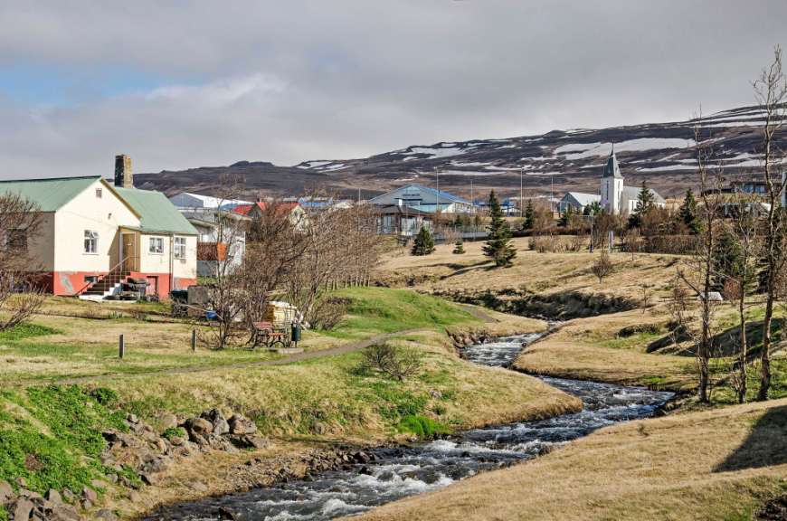 Ein Fluss fließt durch ein Dorf mit einer Kirche im Hintergrund